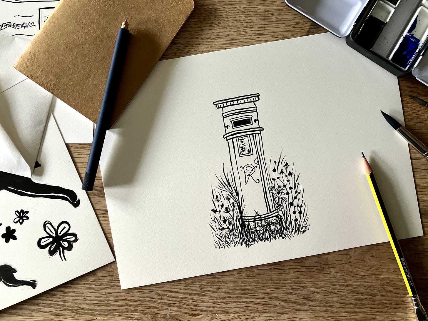 painting of post box surrounded by wild flowers sits atop a table surrounded by other paint materials and paintings