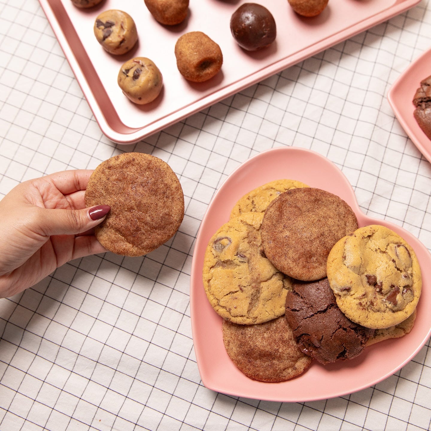 a pink heart shaped plate loaded with a variety or cookies and a tray of cookie balls ready to be baked a pink heart shaped plate loaded with a variety or cookies and a tray of cookie balls ready to be baked