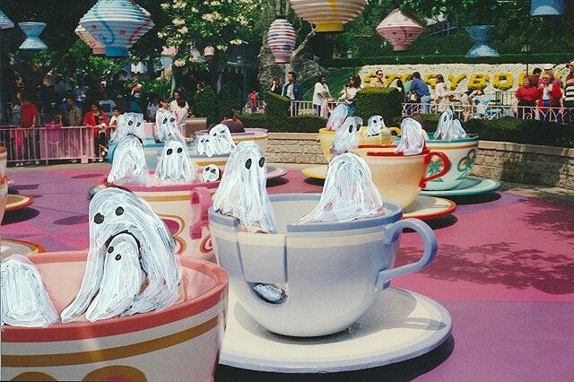 This may contain: there are many cups that have ghost heads in them on the table at this amusement park