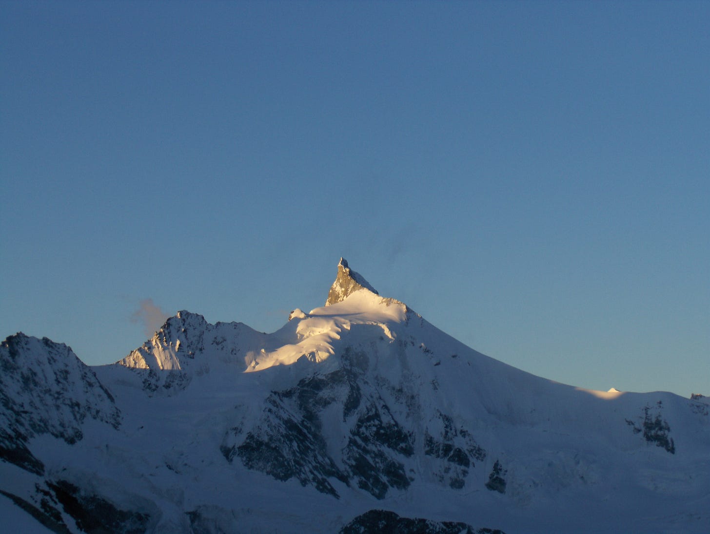 pointy mountain, rock and snow, against blue sky, sunrise