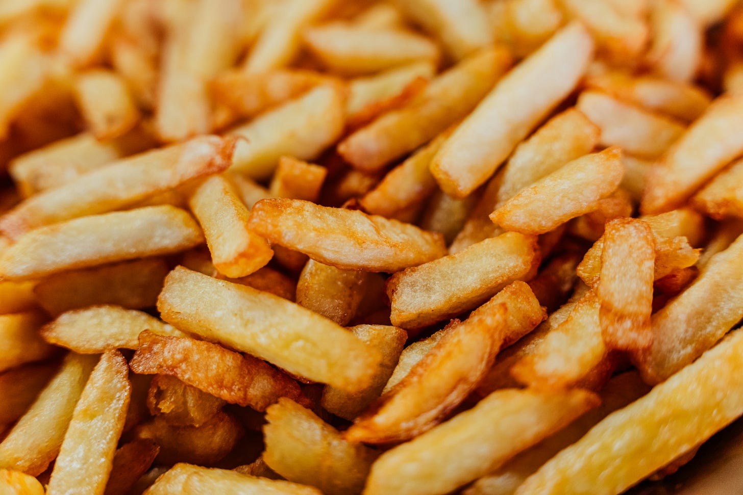 a pile of Belgian chips, golden brown, the perfect thickness and crispy as anything. Photo is close-up so no details of background.