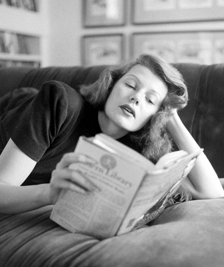 This may contain: a woman laying on a couch reading a book This may contain: a woman laying on a couch reading a book