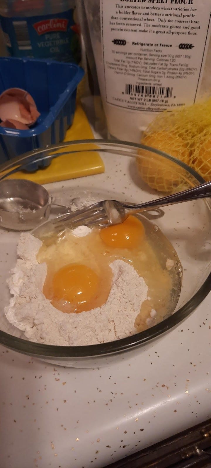 Flour and egg in a glass bowl with a metal fork. Beginning.