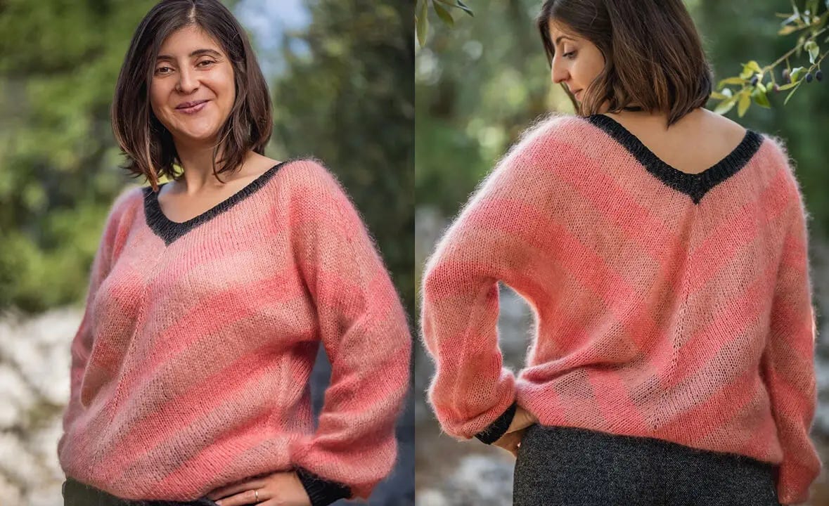 woman smiling standing in front of trees wearing a pink striped sweater with a black neckband