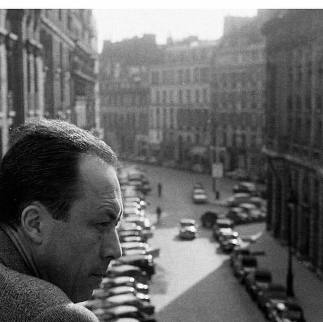 This may contain: a black and white photo of a man looking out the window at cars parked in front of him This may contain: a black and white photo of a man looking out the window at cars parked in front of him