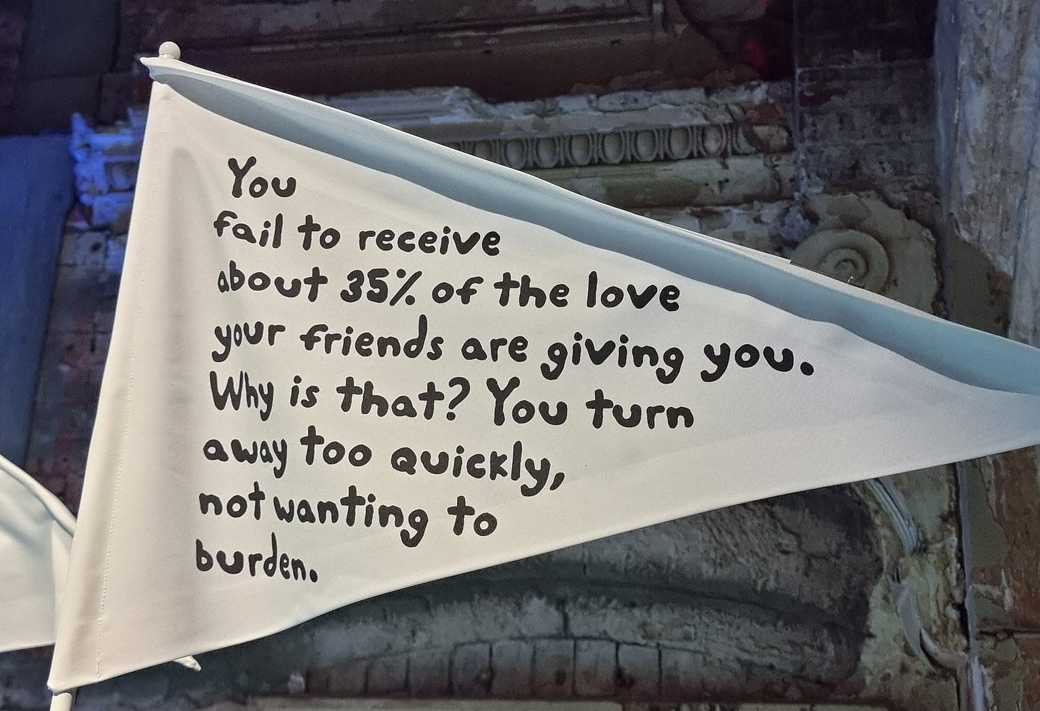 A white, triangular flag reads: "You fail to receive about 35% of the love your friends are giving you. Why is that? You turn away too quickly, not wanting to burden." A white, triangular flag reads: "You fail to receive about 35% of the love your friends are giving you. Why is that? You turn away too quickly, not wanting to burden."