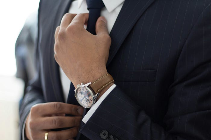 A man in a nice suit and a fancy watch adjusts his tie. Fake compassion in the corporate world creates a toxic culture. A man in a nice suit and a fancy watch adjusts his tie. Fake compassion in the corporate world creates a toxic culture.
