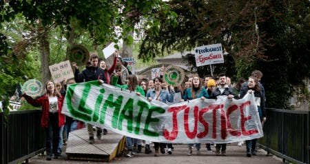 Group of youth protestors marching with a large banner that reads "Climate Justice".