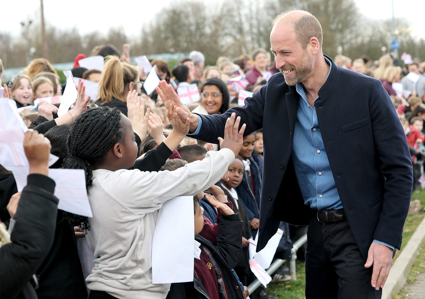 Prince William high-fiving children