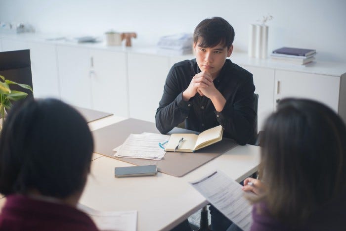 A man with his hands crossed listening to others talk and fill out different things. A man with his hands crossed listening to others talk and fill out different things.