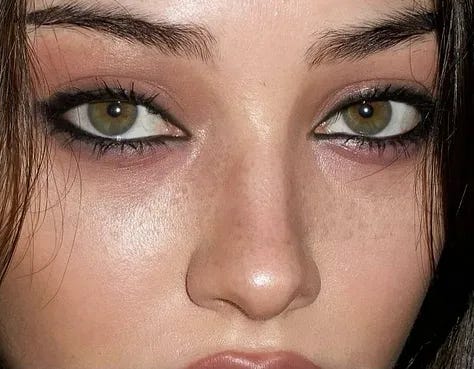 Model wearing smudged black pencil eyeliner for a 2026 messy grunge beauty look.