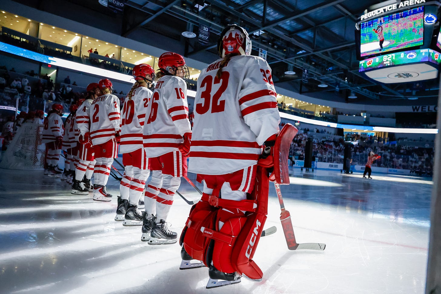 The Wisconsin women's hockey team is seen lined up at their goal line with the house lights off in the arena The Wisconsin women's hockey team is seen lined up at their goal line with the house lights off in the arena