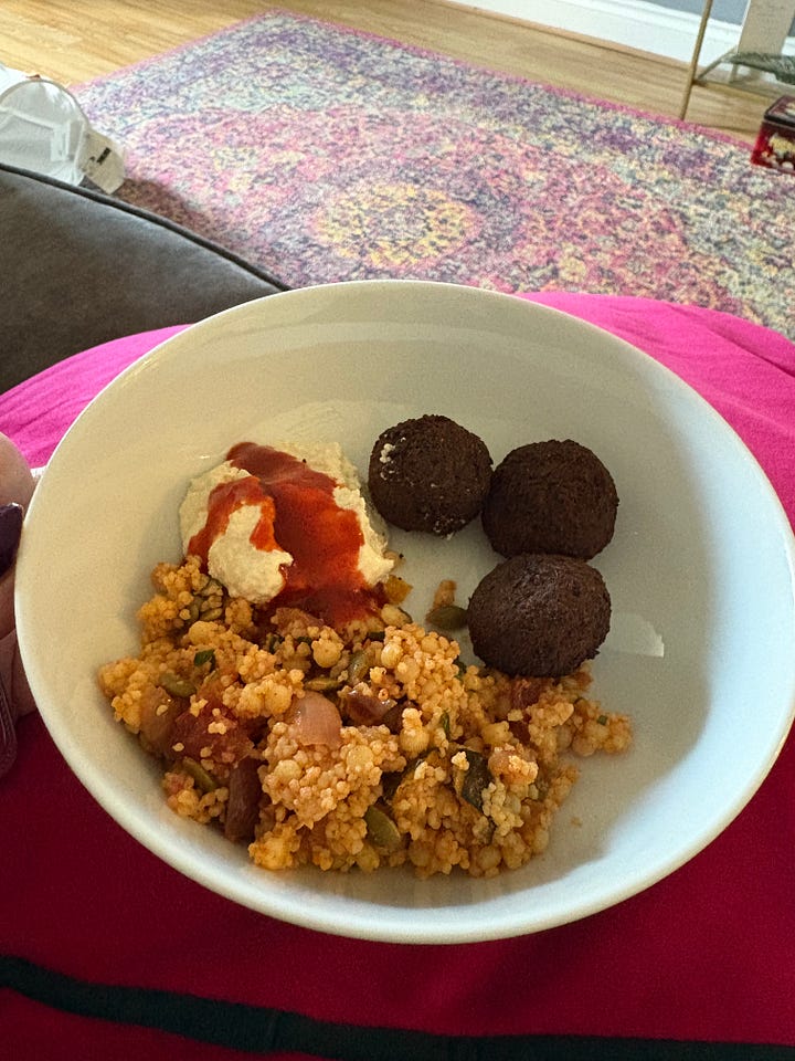 Selfie of Kelly with hair and makeup done ready for work and a bowl with falafel, humous and couc cous for lunch.