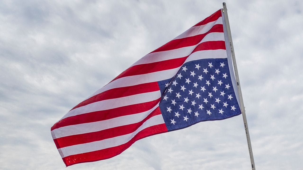 An American flag flies upside down from a flag pole.