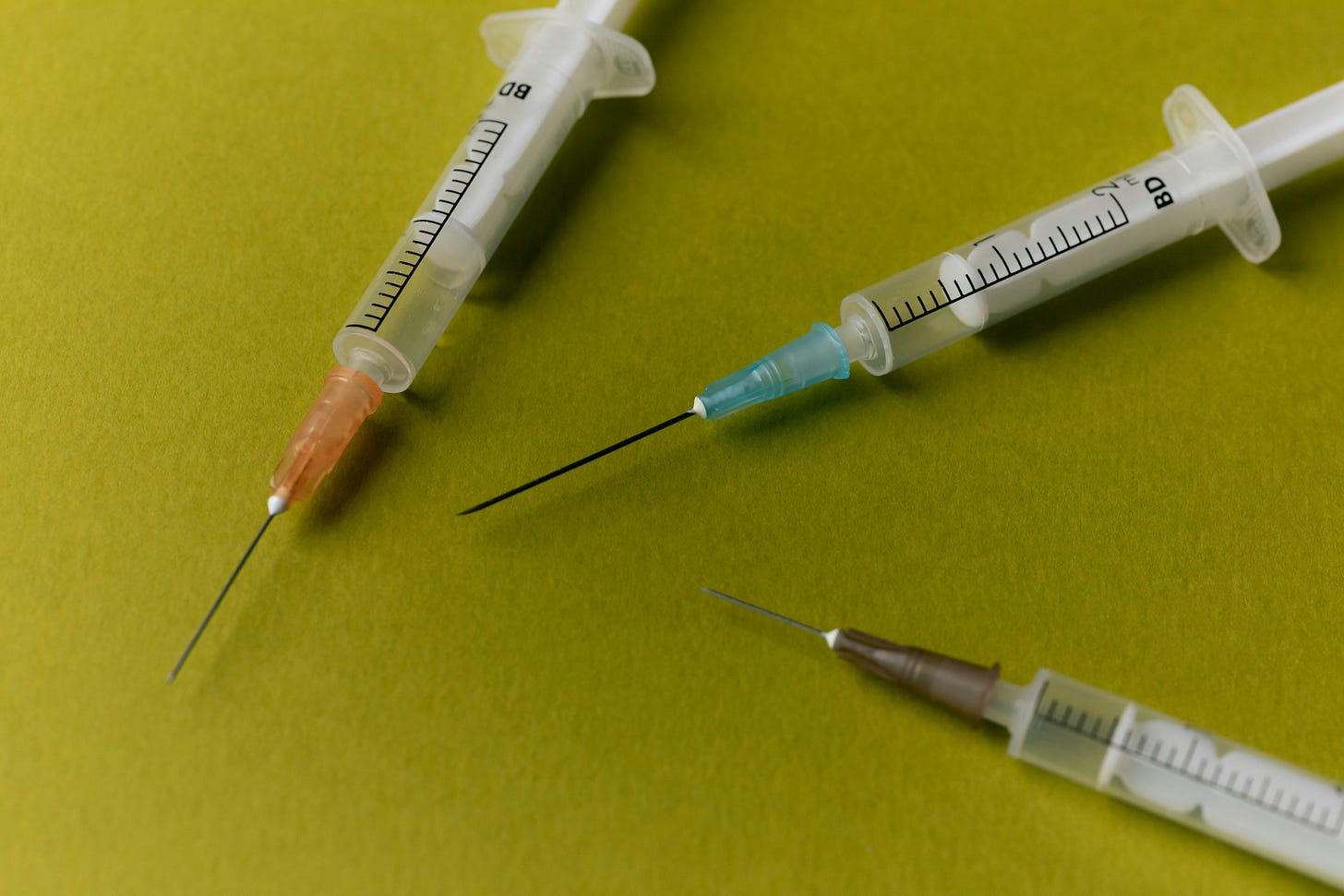 Three empty needles sitting on a green background.