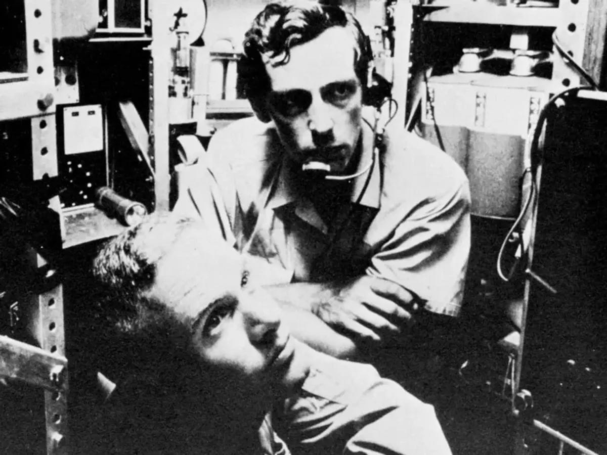 A black and white photo of two men cramped together in an underwater vehicle.   