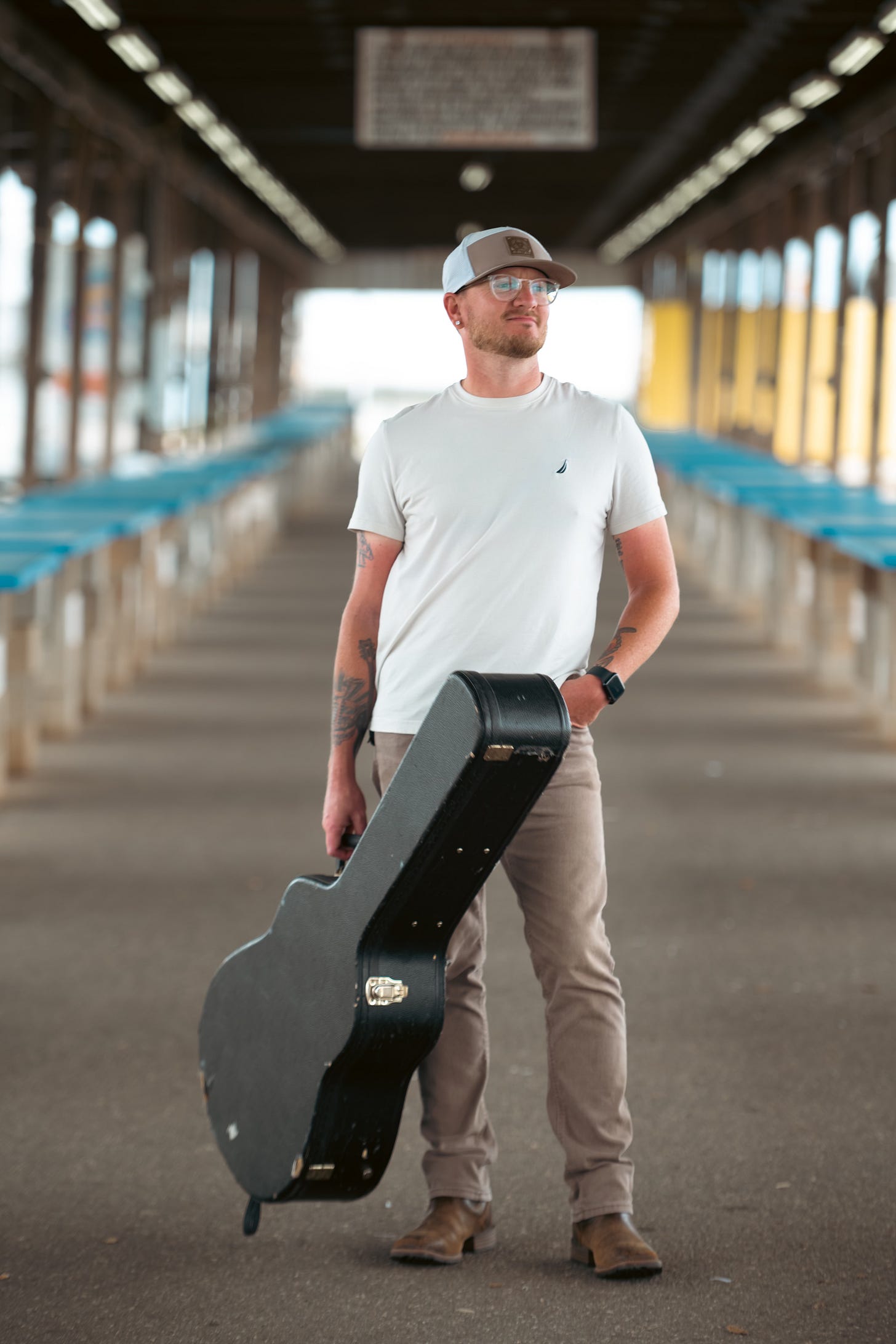 North Carolina recording artist Caleb Wolfe plays his acoustic guitar outdoors, wearing a custom strap with his name and a casual white T-shirt and cap.📸 by Nakeshia Shannon | Shan Media Co. | @ShanMediaco
