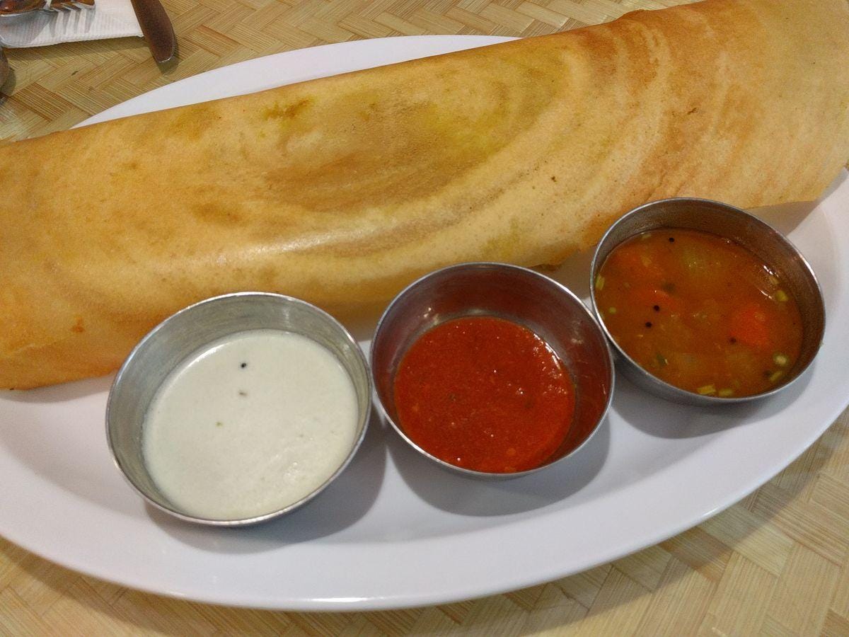 A rolled brown pancake with three sauces.