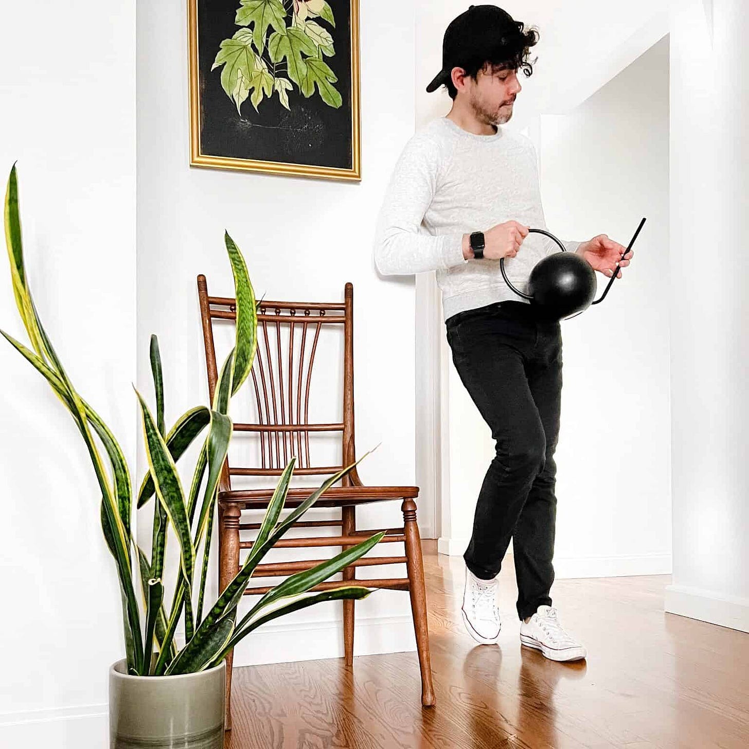 Anthony from 136home is holding a watering can in a room with a snake plant. Anthony from 136home is holding a watering can in a room with a snake plant.
