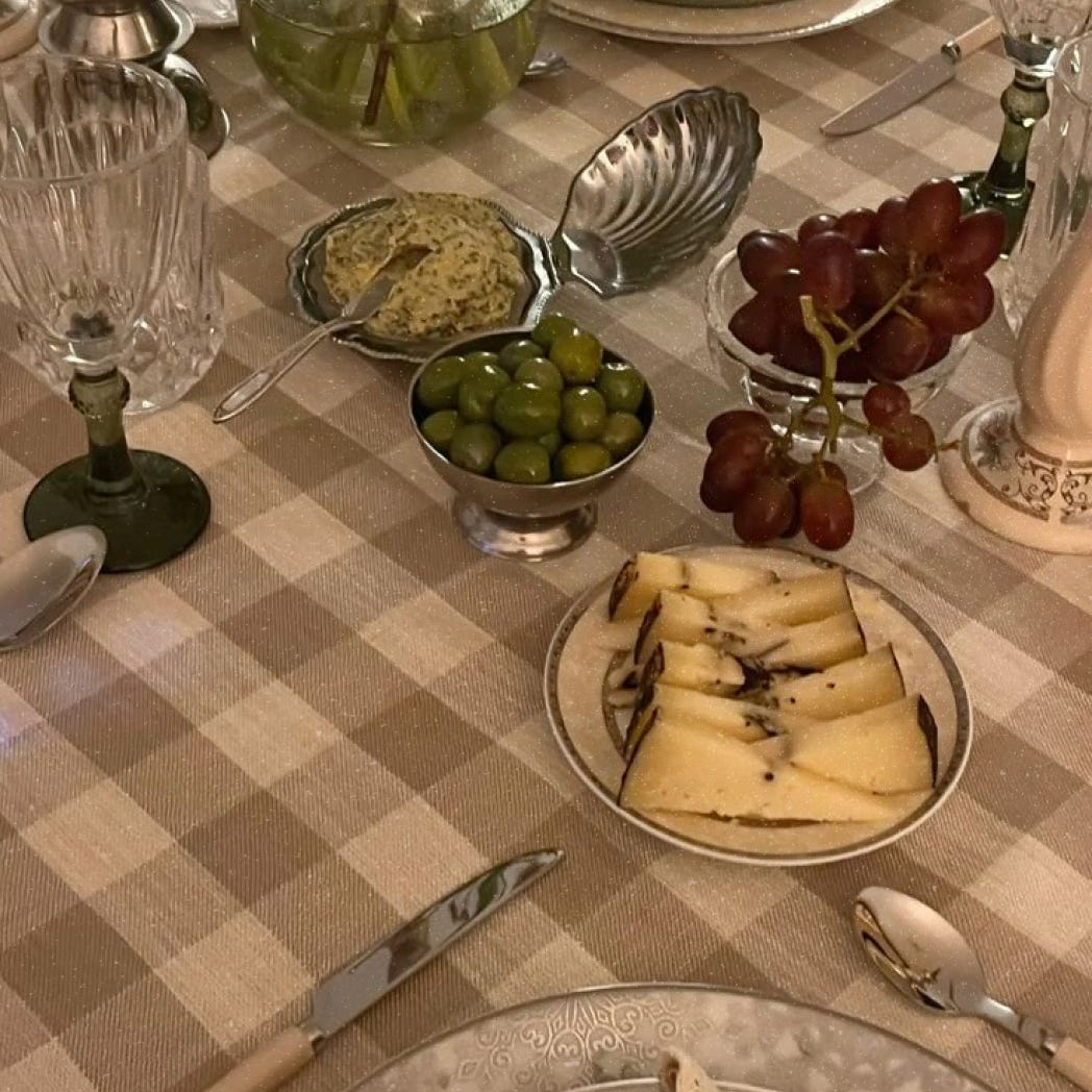 A photograph of a table with olives and cheese on stylish tableware