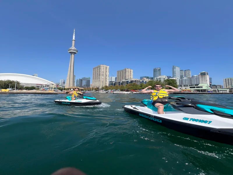 A fish-eye lens photo of two jetski riders in Toronto Harbour, in front of the CN Tower and SkyDome A fish-eye lens photo of two jetski riders in Toronto Harbour, in front of the CN Tower and SkyDome