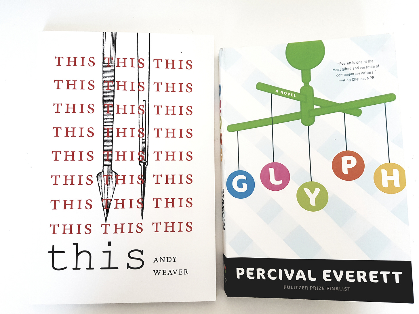 Photo of two books side by side. Andy Weaver's This is to the left of Percival Everett's Glyph, on a white background.