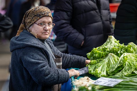 Această galerie se oprește asupra oamenilor din piață: vânzători, legumicultori, femei și bărbați pentru care taraba nu este doar loc de lucru, ci rezultatul unei munci duse luni întregi. Ridurile, privirile, gesturile și răbdarea lor spun o poveste despre efort, continuitate și legătura directă dintre pământ și oraș.