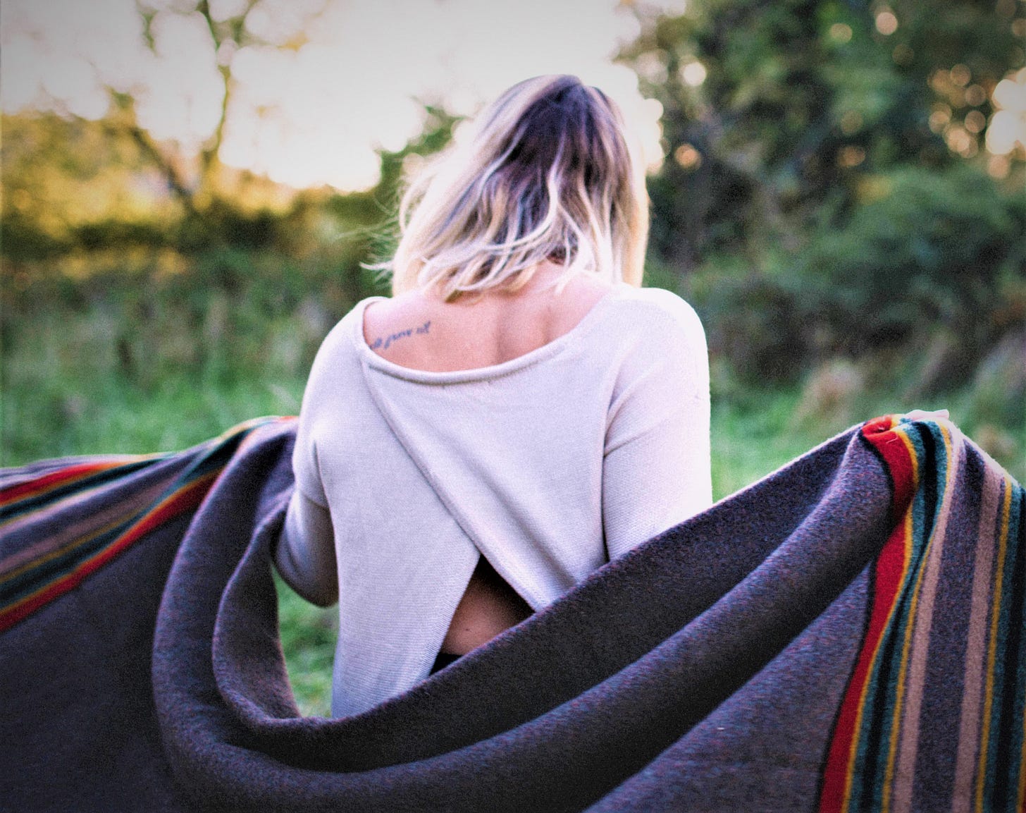 rear view of woman wearing white top with blanket spread behind her rear view of woman wearing white top with blanket spread behind her
