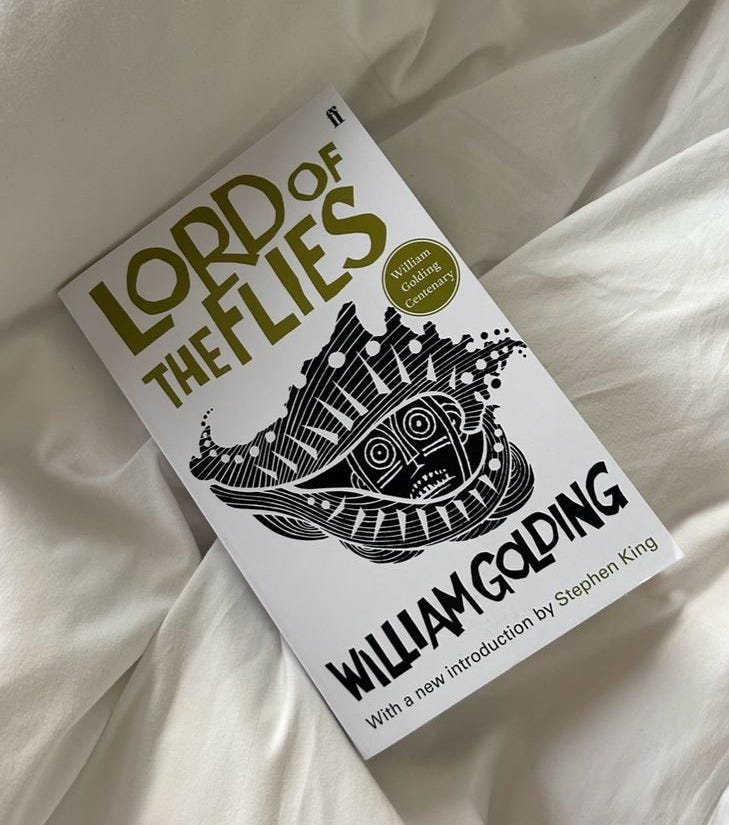This may contain: a book sitting on top of a bed covered in white sheets and pillows with the title lord of the flies written above it