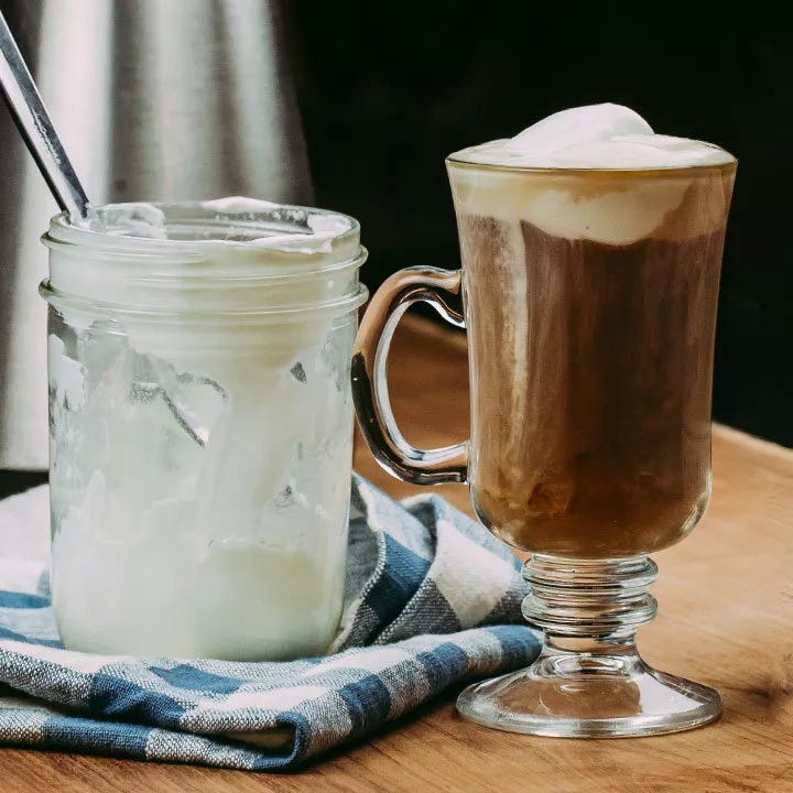 Irish Coffee Cocktail in glass mug next to a jar of cream Irish Coffee Cocktail in glass mug next to a jar of cream