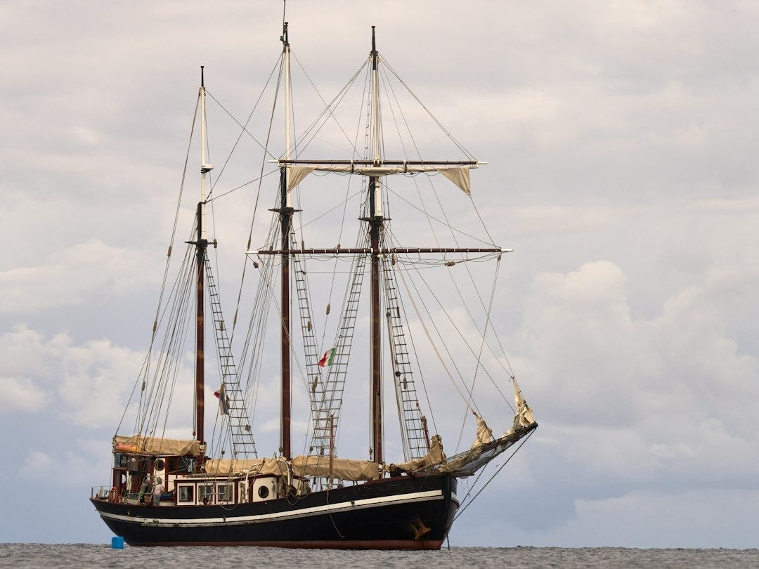 A tall ship sails on a calm sea under clouds. A tall ship sails on a calm sea under clouds.