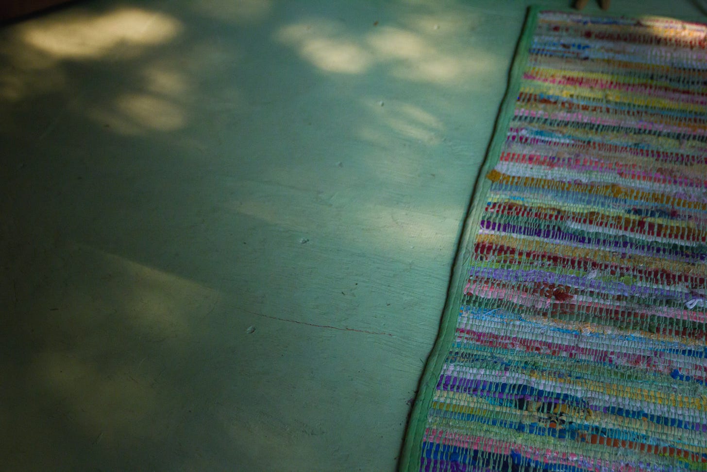 Dappled light upon the wooden floor of a cottage at Lake Huron with a handwoven rug. Credit: Nancy Forde