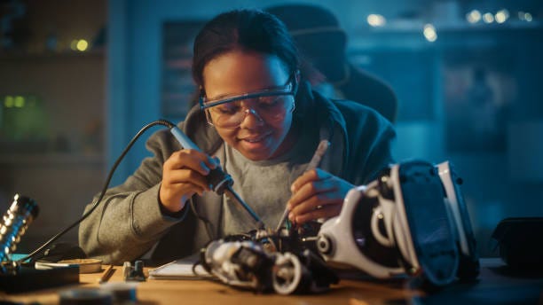 Young Teenage Multiethnic Schoolgirl is Studying Electronics and Soldering Wires and Circuit Boards in Her Science Hobby Robotics Project. Girl is Working on a Robot in Her Room. Education Concept. Young Teenage Multiethnic Schoolgirl is Studying Electronics and Soldering Wires and Circuit Boards in Her Science Hobby Robotics Project. Girl is Working on a Robot in Her Room. Education Concept. student Innovators stock pictures, royalty-free photos & images