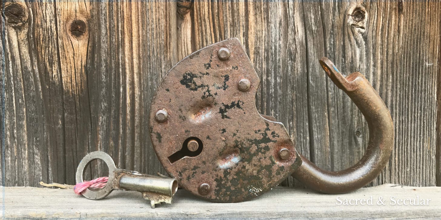 An antique metal key resting beside a rusted, partially opened padlock on a weathered wooden surface. The image evokes themes of curiosity, discovery, and the gradual opening of understanding.