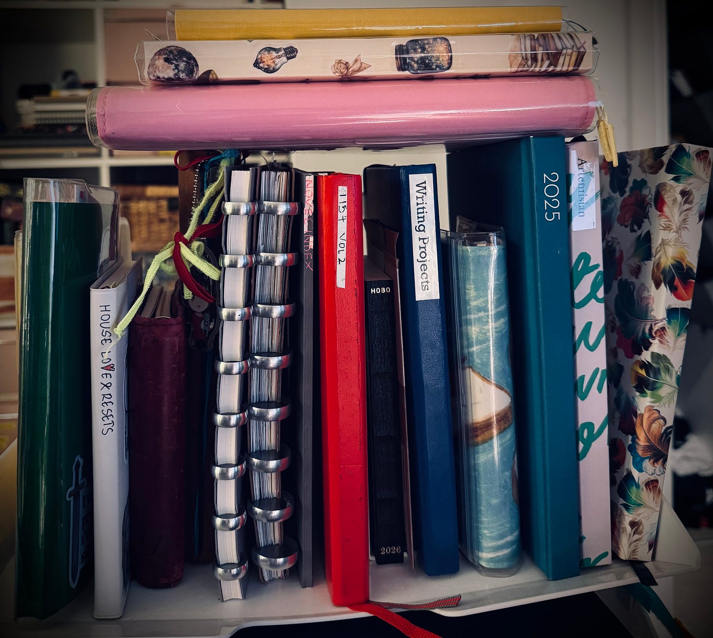 A precariously stacked shelf of notebooks and planners