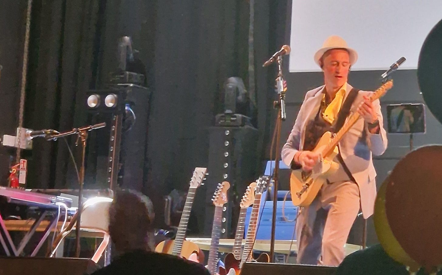 Man in hat playing guitar onstage.