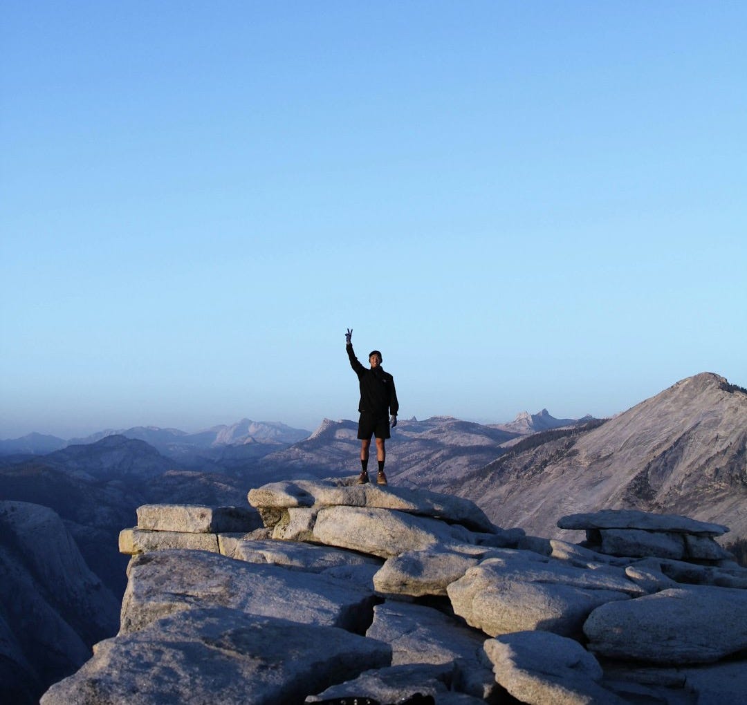 person standing on rocky cliff photography