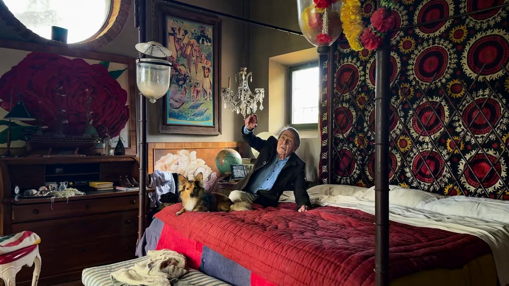 an old man sitting on a bed with a dog