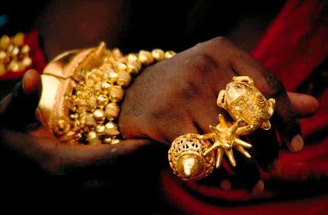 A person's hands and wrist heavily adorned with gold jewellery
