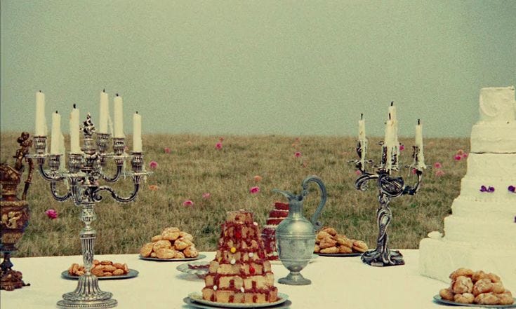 This may contain: a table topped with lots of desserts and candles next to a cake covered in icing