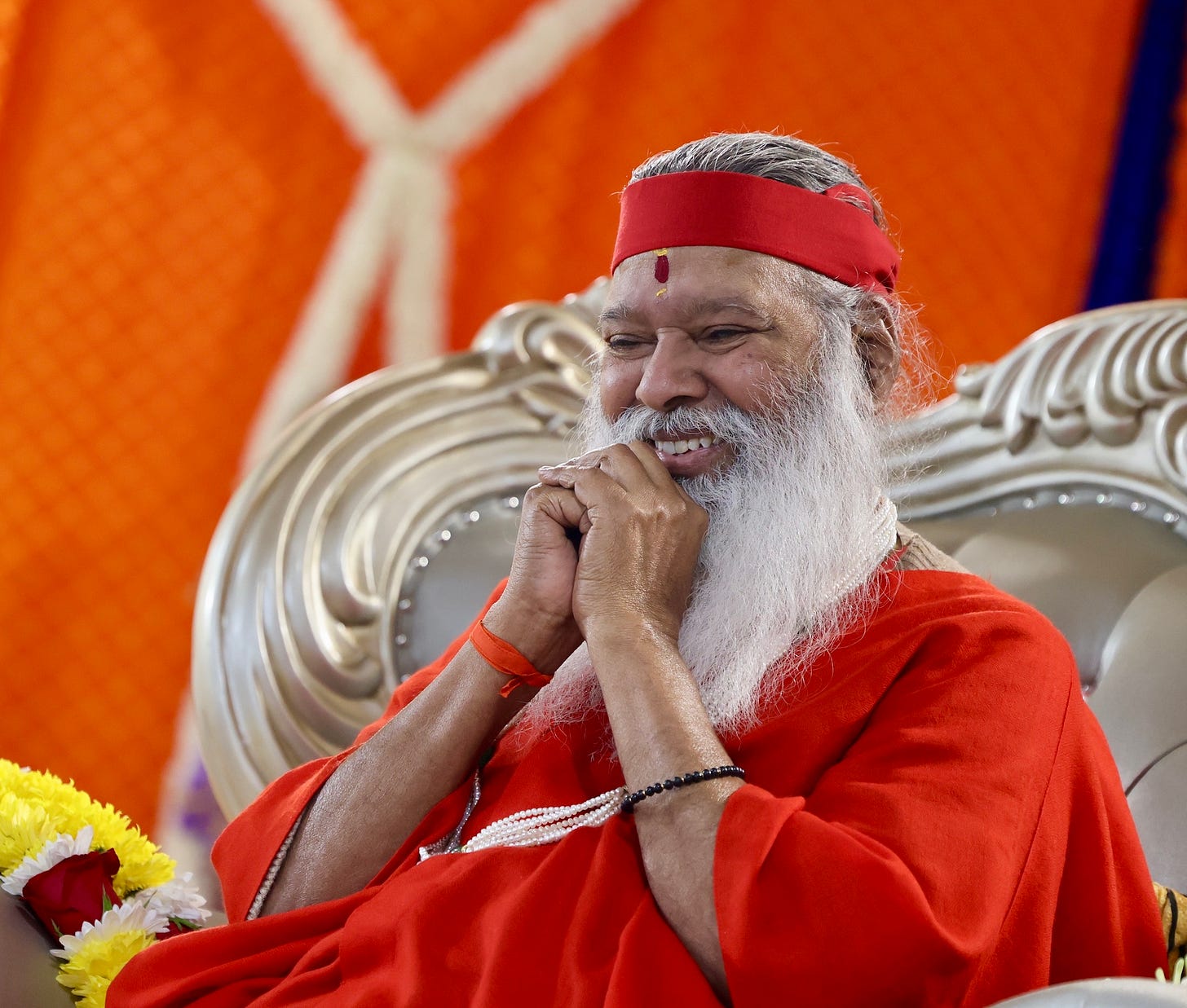 Sri Ganapathy Sachidananda Swamiji, an old Indian man dressed in orange robes, smiles