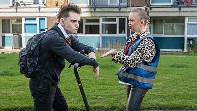 A boy on a scooter and a girl stand in front of some flats arguing