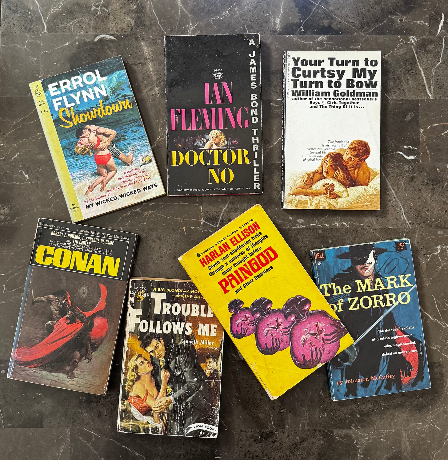 Various paperback books, including Showdown, Doctor No, Your Turn to Curtsy, My Turn to Bow, Conan, Trouble Follows Me, Paingod, and The Mark of Zorro