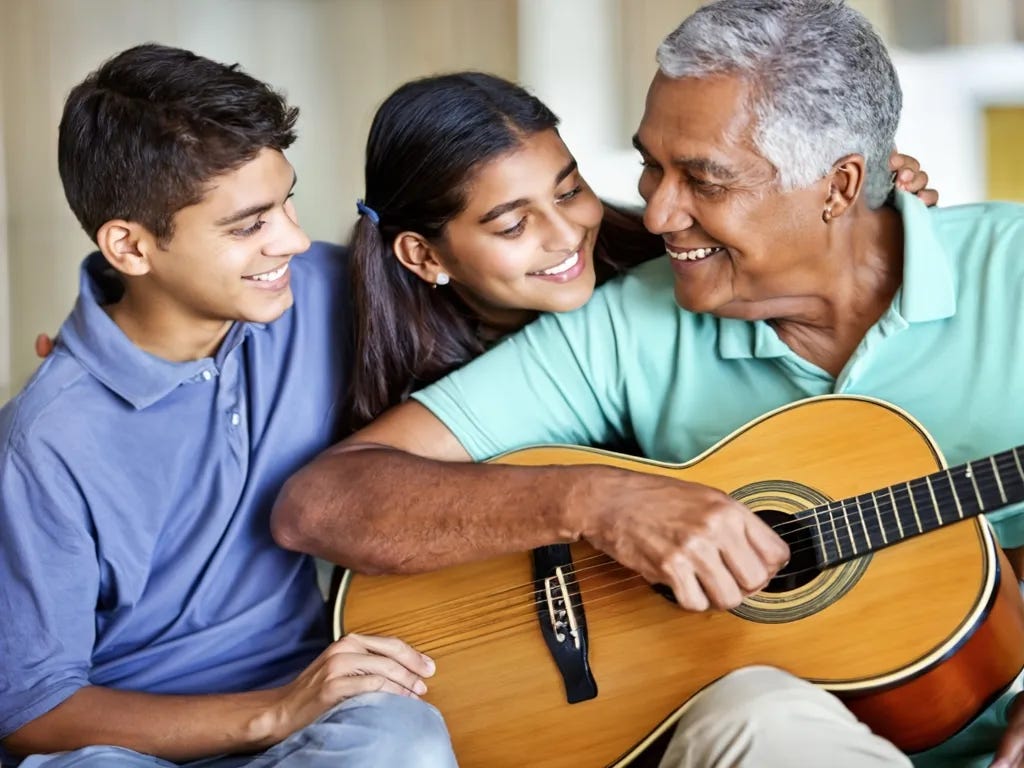 Two pre-teens (a boy and a girl) snuggle up to their grandfather, who has a guitar in his lap and is looking back at them with approval as he sings.