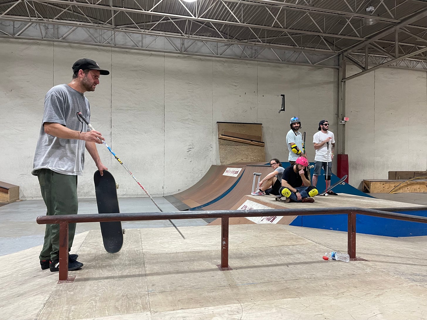 Blind skater Dan Mancina holds his skateboard as he studies the rail with his cane. 3 other blind skaters listen on in the background one of the skaters has a broken leg Blind skater Dan Mancina holds his skateboard as he studies the rail with his cane. 3 other blind skaters listen on in the background one of the skaters has a broken leg