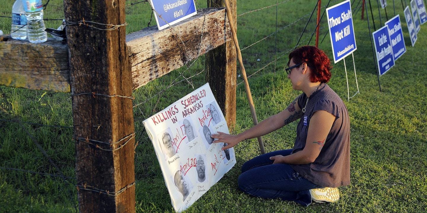 Gina Grimm, daughter of inmate Jack Jones, touches a poster of those condemned to be executed outside the Varner Unit on Monday, April 24, 2017 near Varner, Ark.    Jack Jones and Marcel Williams received lethal injections on the same gurney Monday night, just about three hours apart. It was the first double execution in the United States since 2000.   (Stephen B. Thornton/The Arkansas Democrat-Gazette via AP)
