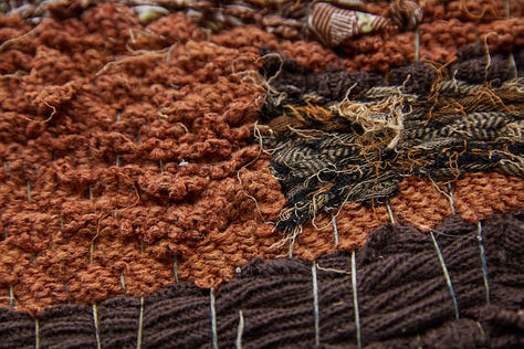 Left image is a close-up of woven textiles in different tones of brown. Center image shows a person walking in the distance towards a mountain, surrounded by trees and water. Right image shows a torn photograph of a kid in costume with their hand waving in the air, on a red background.