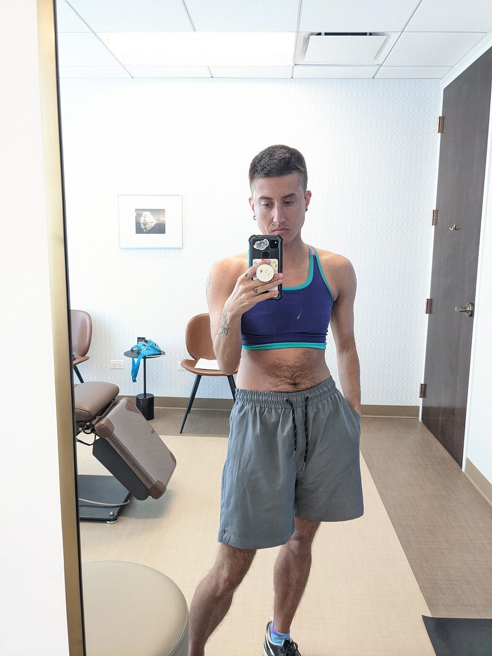 A photo of me in the plastic surgeon’s office with a colorful, transparent mesh Rebirth Garments binder on.