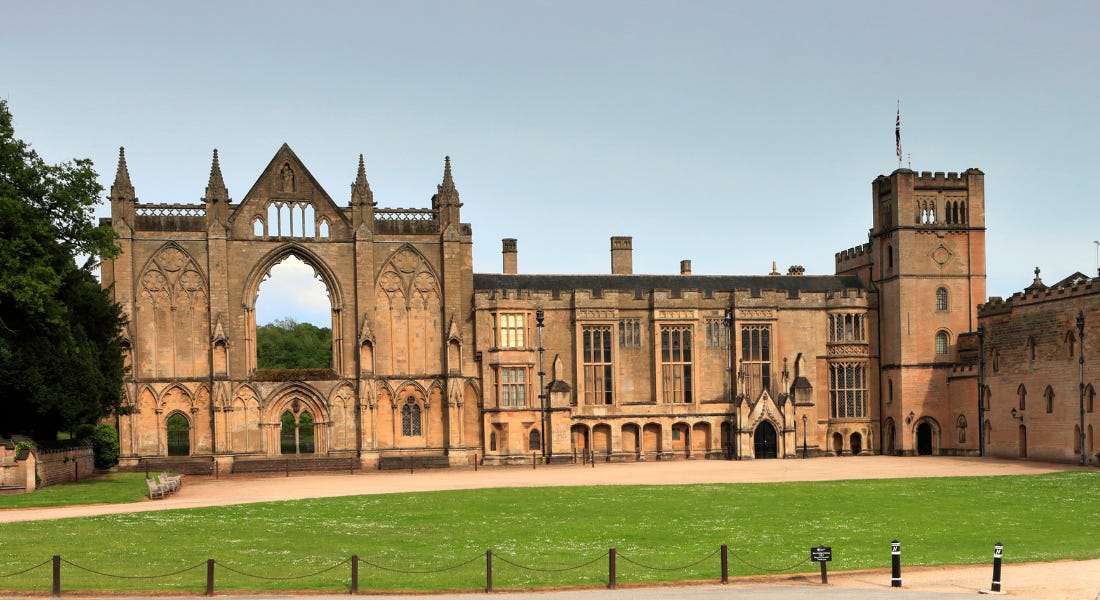 A stone Abbey with a lawn in front of it and a clear blue sky above it A stone Abbey with a lawn in front of it and a clear blue sky above it