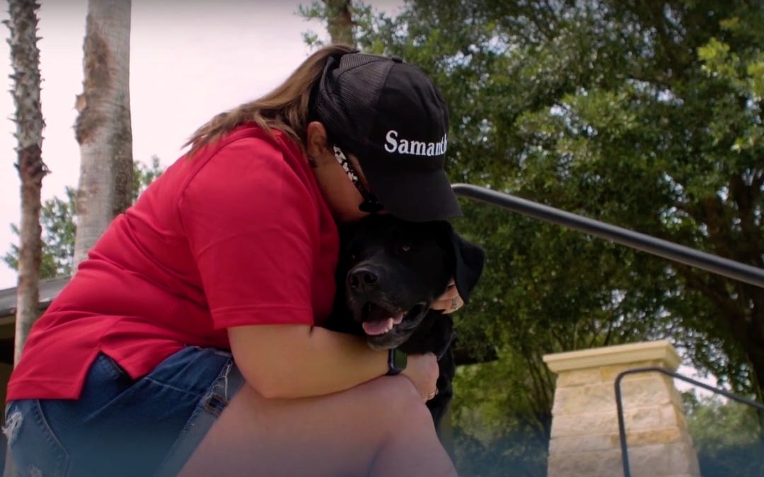 Woman in red shirt hugging a dog